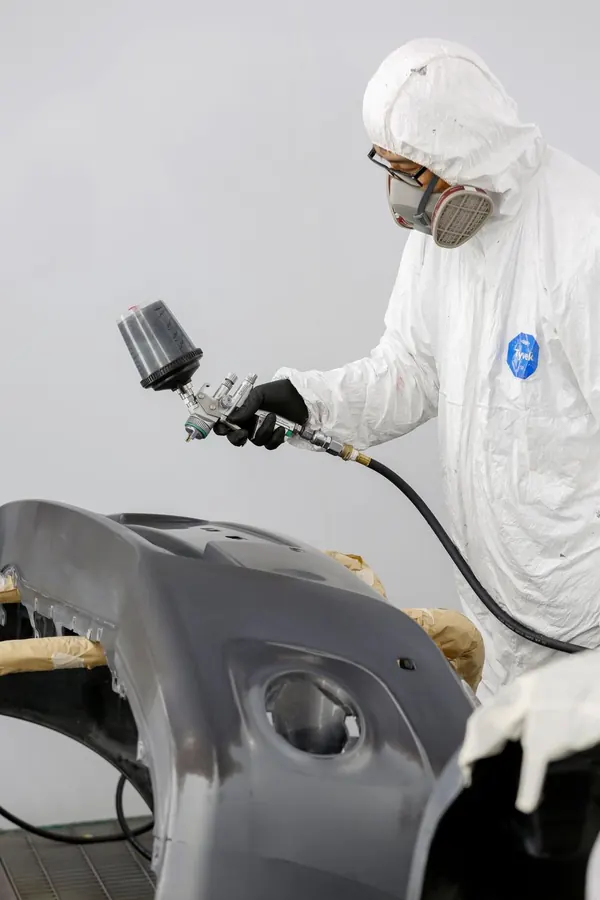 Técnico con traje blanco trabajando un parachoques
